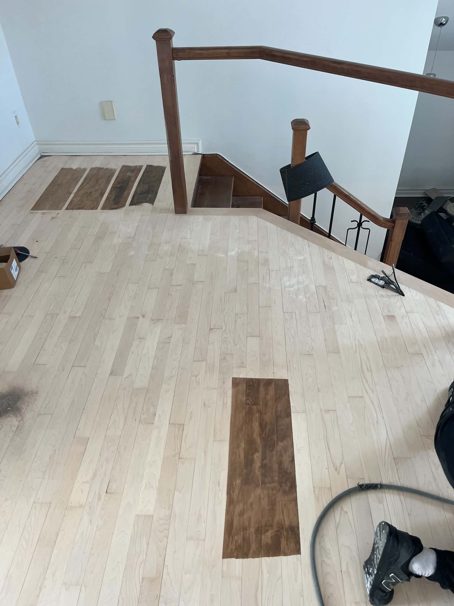 Échantillons de teinture sur un plancher fraîchement sablé, en haut d’un escalier